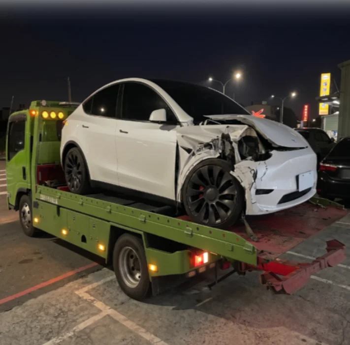 受損白色 Tesla Model Y 上拖板車，電車玩家事故車收購到場服務